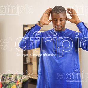 Jeune homme africain musulman , en tenue traditionnelle qui prie.
