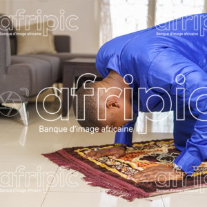 Jeune homme africain musulman , en tenue traditionnelle qui prie