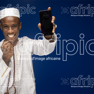 Jeune musulman africain souriant, en tenue traditionnelle, tenant un chapelet et un téléphone