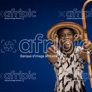 Jeune africain paysan, heureux et amical tenant une canne.