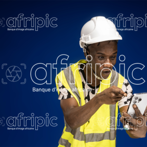 Jeune homme africain heureux et excité , le regard fixé sur son téléphone.