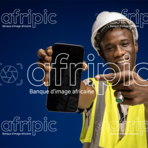 Jeune homme africain souriant en tenue de travail montrant l'écran de son téléphone