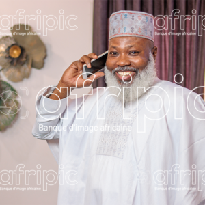 Homme africain senior , en communication téléphonique, dans son salon