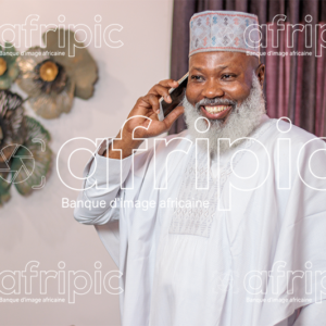 Homme africain senior , en communication téléphonique, dans son salon