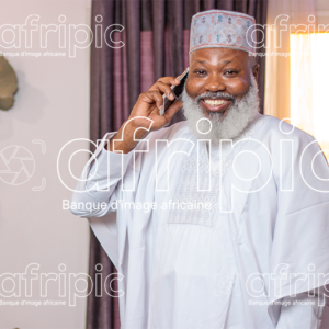 Homme africain senior , en communication téléphonique, dans son salon