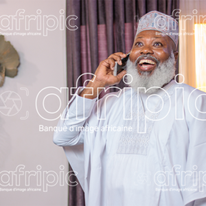 Homme africain senior , en communication téléphonique, dans son salon