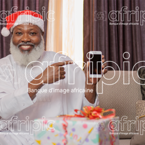 Homme africain senior, en période de fête, montrant l'écran de son téléphone