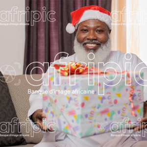 Homme africain senior souriant, tenant un cadeau