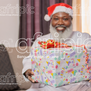 Homme africain senior souriant, tenant un cadeau