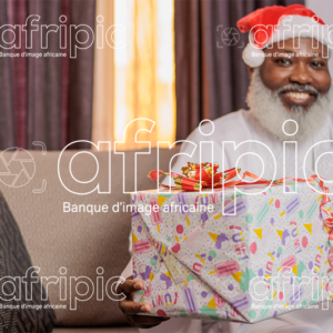 Homme africain senior souriant, tenant un cadeau