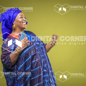 Femme senior africaine, heureuse avec un téléphone à la main. Technologie, Informatique, transfert d’argent, Commerce en ligne, E-learning, Tenue traditionnelle