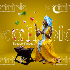 Jeune femme africaine toute heureuse, faisant de la grillade pour la Tabaski