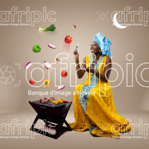 Jeune femme africaine toute heureuse, faisant de la grillade pour la Tabaski
