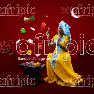 Jeune femme africaine toute heureuse, faisant de la grillade pour la Tabaski