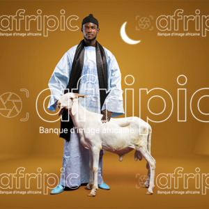 Jeune homme africain en tenue traditionnelle, avec son mouton de tabaski