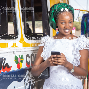 Femme jeune en tenue traditionnelle avec un téléphone à la main devant un car rapide