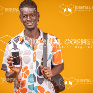 Jeune homme africain souriant, avec un sac de voyage, montrant l'écran de son téléphone, sur fond orange